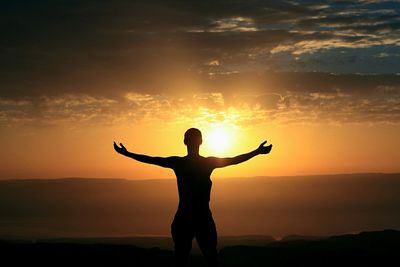 Silhouette man standing against orange sky during sunset