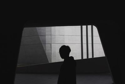 Silhouette woman standing against window