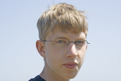 Close-up portrait of teenage boy against clear sky