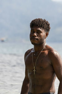 Portrait of shirtless man standing at beach