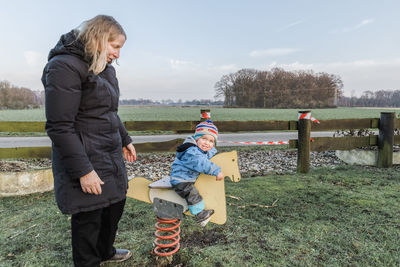 Grandmother looking at granddaughter sitting on spring ride