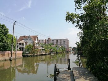 Buildings by river against sky