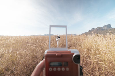 Man photographing on field against sky