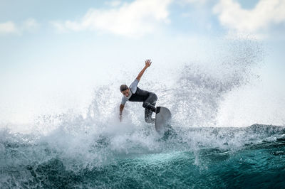 Teenager boy surfing in sea against sky