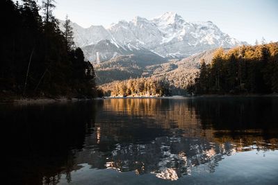 Scenic view of lake by snowcapped mountains against sky