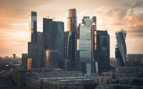 Modern buildings in city against sky during sunset