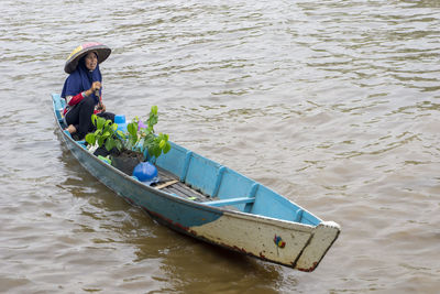 High angle view of woman with plant on boat in lake