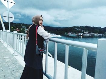 Woman standing by railing against sky