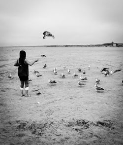 Full length of woman on seagull at beach against sky