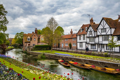 Houses by river and buildings against sky