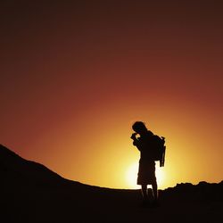 Silhouette of man standing against clear sky at sunset