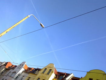 Low angle view of vapor trails against clear blue sky