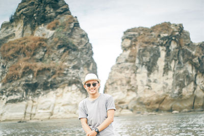 Portrait of man wearing sunglasses standing on rock