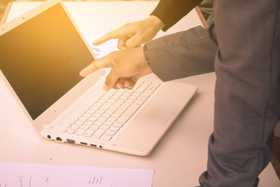 Midsection of man using laptop on table