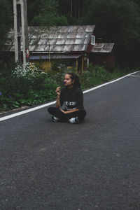 Full length of woman sitting on road