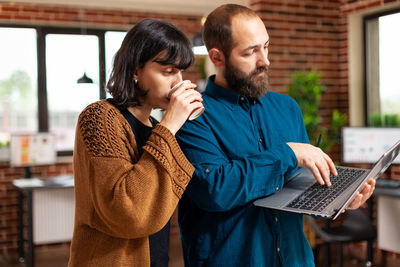 Side view of young man using mobile phone while standing in cafe