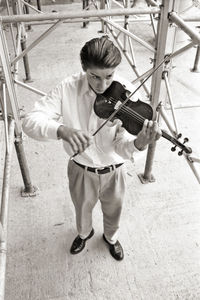 High angle view of man playing violin while standing on footpath