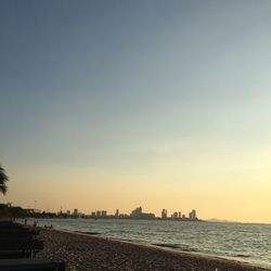 Scenic view of sea by buildings against sky during sunset