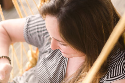 High angle view of young woman relaxing on hammock at home