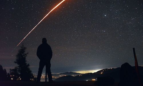 Low angle view of silhouette man standing against star field