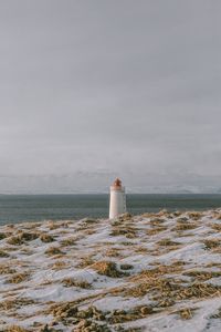 Lighthouse by sea against sky