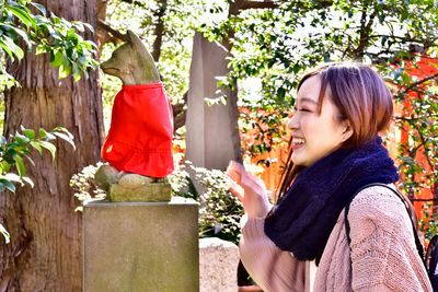 Side view of smiling young woman against plants