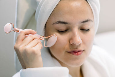 Close up of woman with her eyes closed massaging her face with a quartz roller