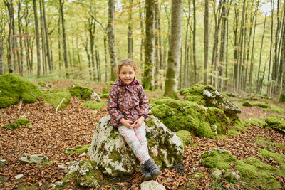 Joyful small kid in warm clothes looking at camera and smiling while s