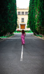 Rear view of woman standing on road in city