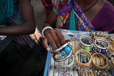 Midsection of woman selling bangles at market