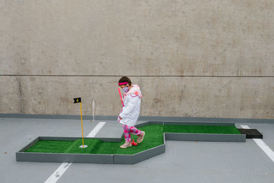 Girl in pink doctor costume and face mask playing mini golf