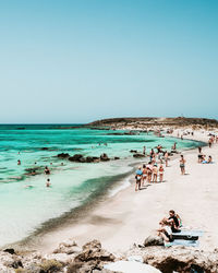 People on beach against clear sky