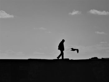 Silhouette man and woman standing against sky