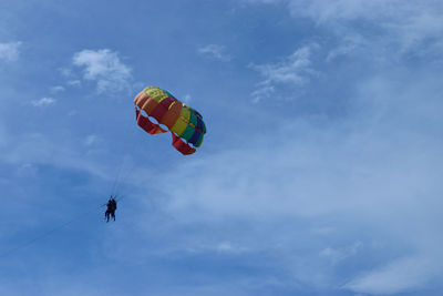 Low angle view of person parasailing against sky