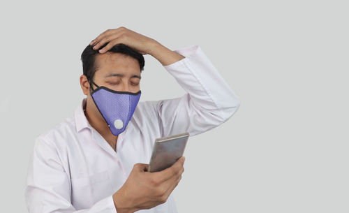 Portrait of man using smart phone against white background