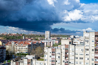 Stormy sky and rainy clouds above a quarter of city residential buildings