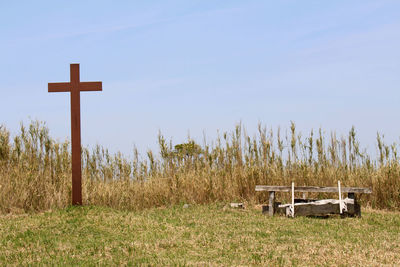 Cross on field against sky