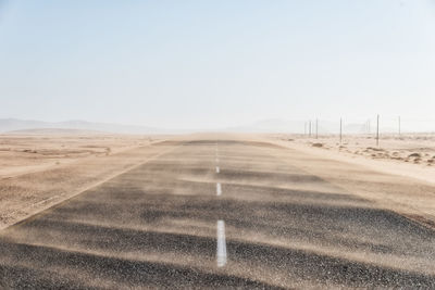 Road amidst desert against clear sky