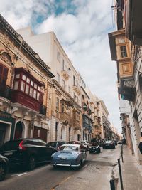 Cars on street amidst buildings in city against sky