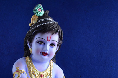 Close-up portrait of statue of buddha against blue background