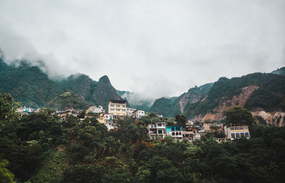 Buildings on mountain during foggy weather