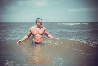 Shirtless man standing in sea