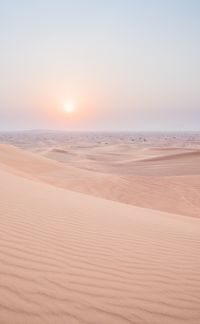 Scenic view of sand dunes against sky during sunset