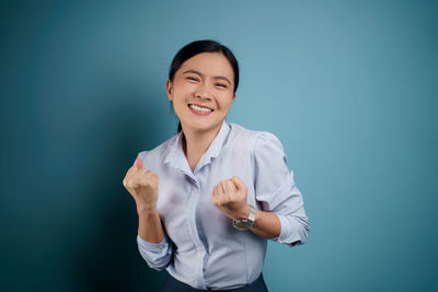 Smiling young woman against blue background