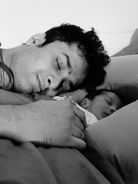 Man sleeping with baby boy on bed at home