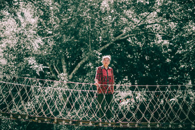 Portrait of senior woman standing on suspension bridge