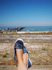 Low section of woman on beach against clear sky