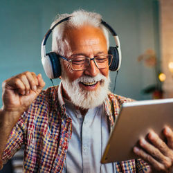 Portrait of a grandpa enjoying the music on his ipad using digital tablet at home