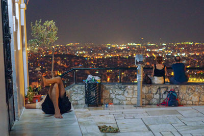 Rear view of woman looking at illuminated city at night