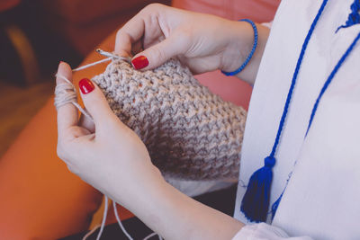 Midsection of woman knitting wool at home